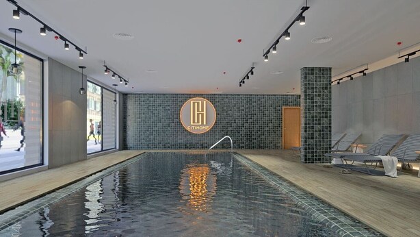 A modern indoor swimming pool with a tiled wall, a logo, and lounge chairs. - Brand New Executive Suite - Close to Airport, Swimming Pool, Gym (Gibraltar)