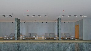 A modern indoor pool area with lounge chairs, a tiled wall, and a wooden door. - Brand New Executive Suite - Close to Airport, Swimming Pool, Gym (Gibraltar)