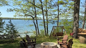 Ein Campingplatz am Seeufer mit Adirondack-Stühlen, einer Feuerstelle und einem Picknicktisch.