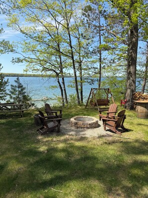 A lakeside campsite with Adirondack chairs, a fire pit, and a picnic table. - "West View Cabins" on Ostego Lake - Cabin #3 - Waterfront and on Trail 7 (Gaylord)