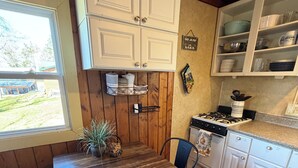 Un tavolo da pranzo in legno con sedie, una cucina con mobili bianchi, un fornello e una finestra con vista sul panorama esterno.