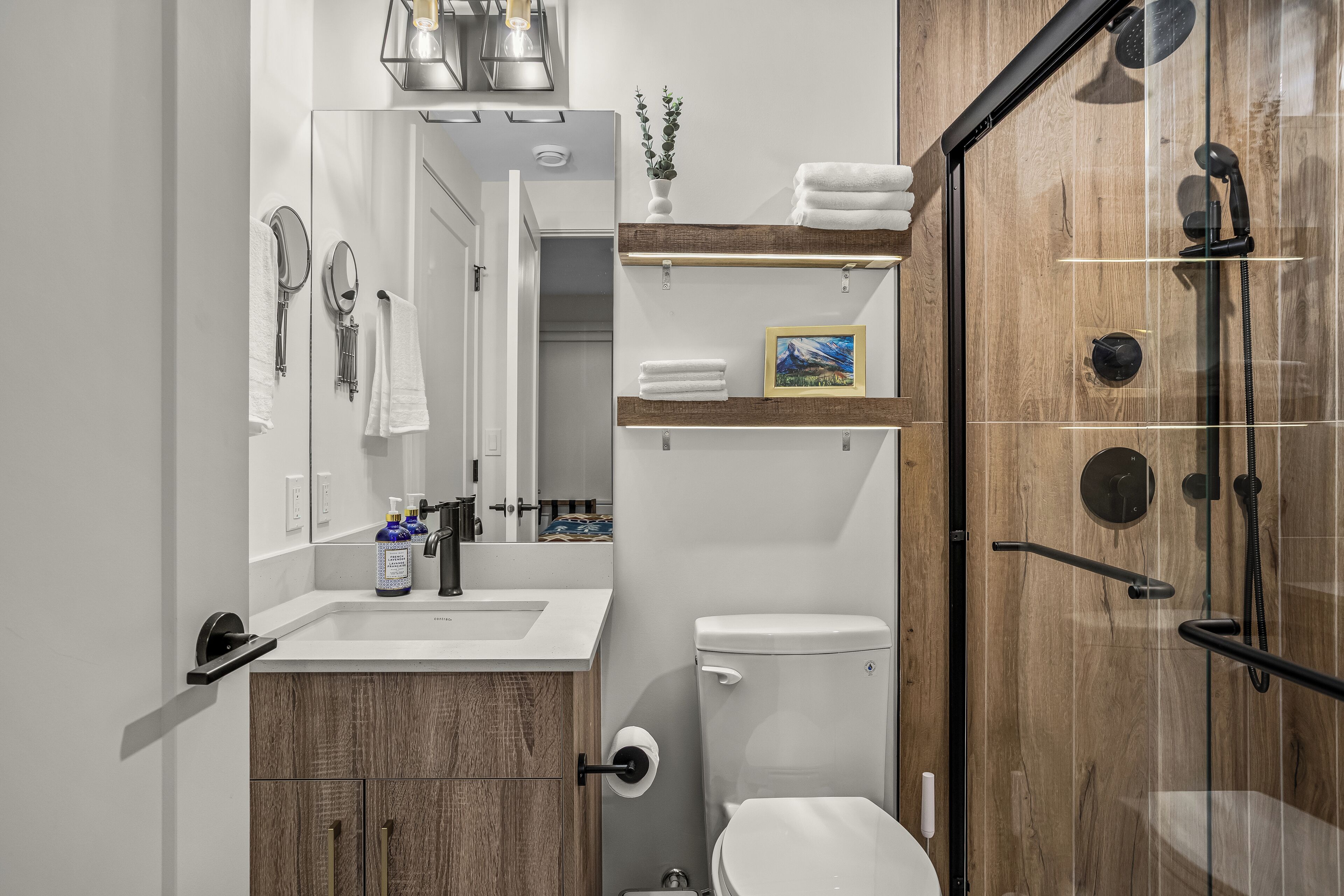 Une salle de bain moderne équipée d’une douche, de toilettes, d’un lavabo et d’un meuble-vasque.