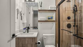 Une salle de bain moderne équipée d’une douche, de toilettes, d’un lavabo et d’un meuble-vasque.