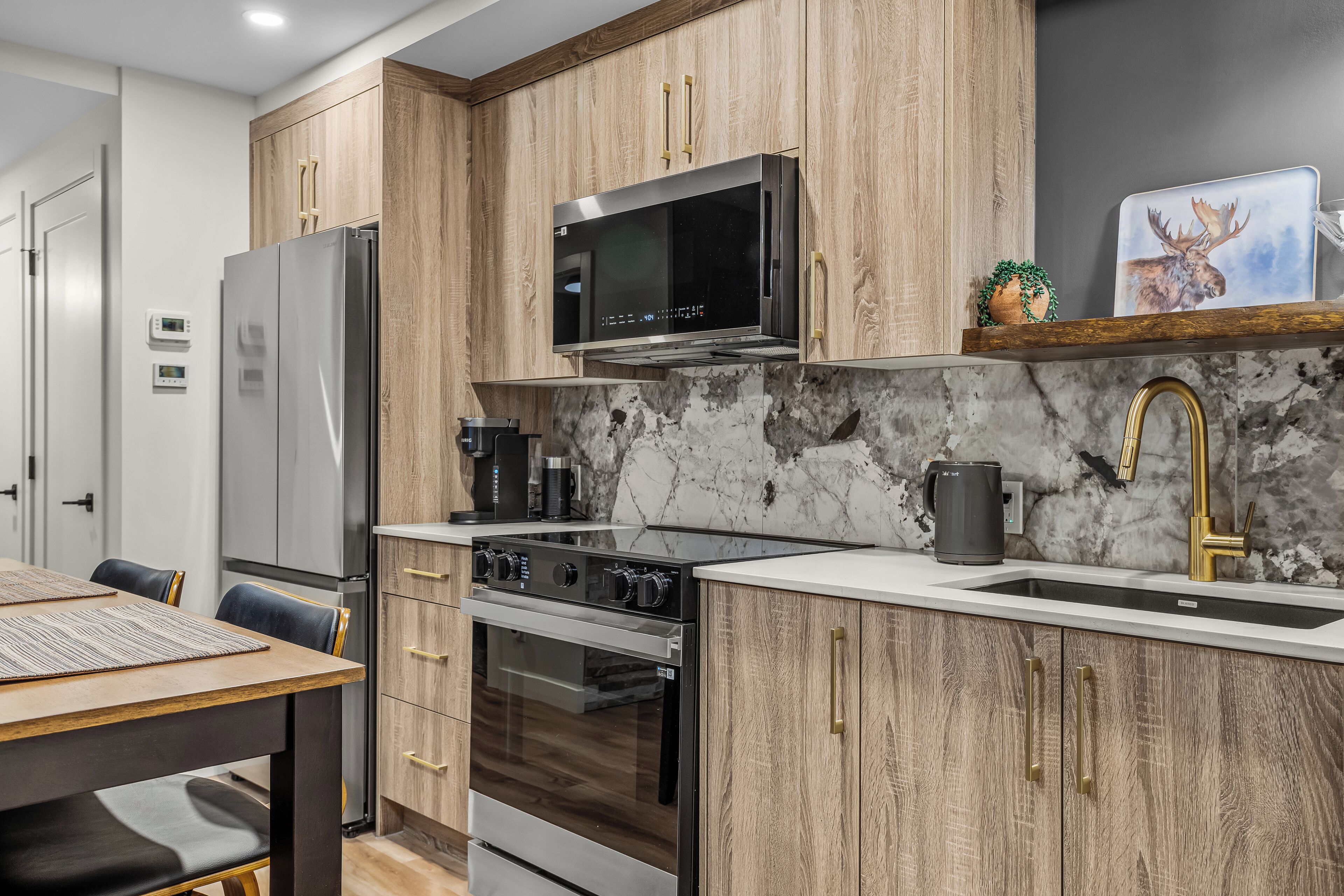 A modern kitchen with wooden cabinets, stainless steel appliances, and a marble backsplash.