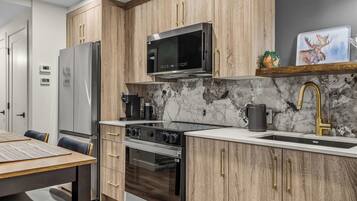 A modern kitchen with wooden cabinets, stainless steel appliances, and a marble backsplash.