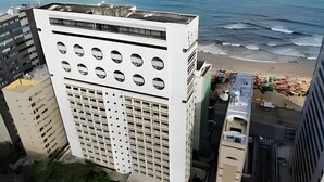 Un immeuble de grande hauteur avec une façade constituée d’une grille de fenêtres et offrant une vue sur la plage.