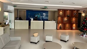 Un hall d’hôtel moderne avec un comptoir d’accueil, un espace salon et un sapin de Noël.