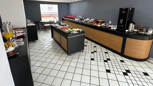 A modern kitchen with a buffet setup, a coffee machine, and a view of a building outside.