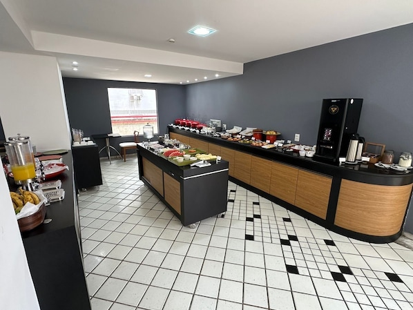 A modern kitchen with a buffet setup, a coffee machine, and a view of a building outside.