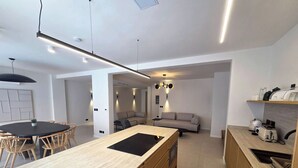 Uma cozinha moderna com uma ilha central, armários de madeira e uma área de jantar com mesa redonda e cadeiras.