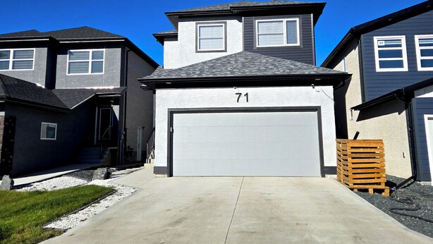 A residential street with houses, a garage, and a driveway. - Stylish New 2BR Suite | Private Entry | Quiet, Near Shops & Transit (Winnipeg)