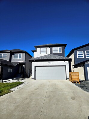 A residential street with houses, a garage, and a driveway.