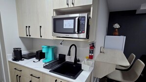 A compact kitchen with a microwave, sink, and a small dining area. - Stylish New 2BR Suite | Private Entry | Quiet, Near Shops & Transit (Winnipeg)