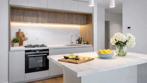 Een moderne keuken met een centraal eiland, een ingebouwde oven en een houten spatwand.
