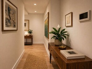 A hallway with a wooden bench, a potted plant, framed artwork, and a book titled 'JOSEF KIBERS' on the right. - Level 69 Bay Views & Japanese Soaking Tub (Melbourne)