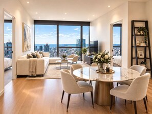 A modern living room with a city view, a dining area with a marble table, and a cozy seating arrangement. - Level 69 Bay Views & Japanese Soaking Tub (Melbourne)