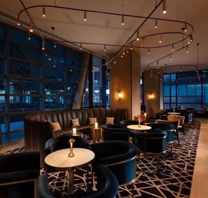 A modern lounge area with leather seating, round tables, and pendant lighting. - Level 69 Bay Views & Japanese Soaking Tub (Melbourne)