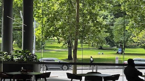 Een restaurant met grote ramen en uitzicht op een park en straat.