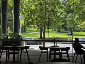 En restaurang med stora fönster som ger utsikt över en park och en gata.