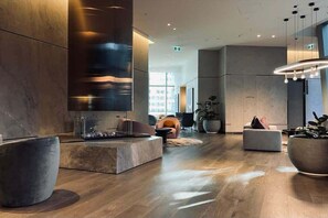 A modern lobby with a stone fireplace, seating areas, and a large potted plant. - Level 69 Bay Views & Japanese Soaking Tub (Melbourne)