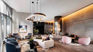 Een moderne lobby met een grote kroonluchter, zithoeken en een groot televisiescherm.