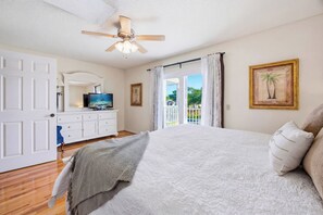 A bedroom with a bed, a TV, a ceiling fan, a dresser, and a view of the outdoors. - Peaceful end-unit townhome in Miramar Beach (Miramar Beach)