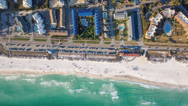 Luchtbeeld van een kusthotel met strand, parkeerplaats en zwembad.