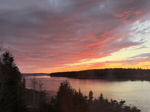 Un lac bordé d’une forêt et un ciel au coucher du soleil.