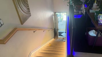 A staircase with a wooden finish, a metal handrail, and a door leading outside.