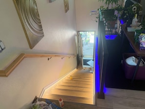 A staircase with a wooden finish, a metal handrail, and a door leading outside. - 3-bedroom house in soothing Anchorage perfect for your getaway (Anchorage)