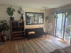 A living room with a sofa, a wooden entertainment unit, a large mirror, and a fan. - 3-bedroom house in soothing Anchorage perfect for your getaway (Anchorage)