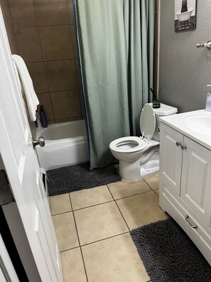 A bathroom with a toilet, bathtub, shower curtain, and a towel rack. - 3-bedroom house in soothing Anchorage perfect for your getaway (Anchorage)