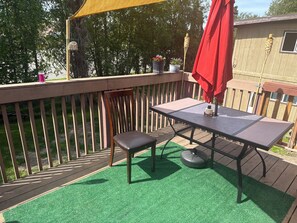 A deck with a table and chairs, surrounded by a wooden fence and greenery. - 3-bedroom house in soothing Anchorage perfect for your getaway (Anchorage)