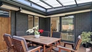 En terrasse med et træbord og stole, grill og en potteplante.