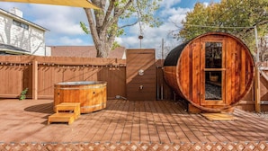 Een houten jacuzzi, een houten, vatvormig bouwwerk en een terras met traptreden.