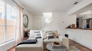 Een moderne woonkamer met een bank, salontafel en een trap naar een hoger niveau.