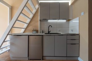 A compact kitchen with a built-in dishwasher, a sink, and a ladder leading to an upper level. - Dietla Apartment Kraków (Kraków)