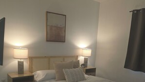 A bedroom with a bed, two bedside tables with lamps, a headboard, a rug, and a painting on the wall. - Spacious 3-bedroom house in serene Cleveland with AC (Cleveland)