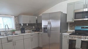 A modern kitchen with stainless steel appliances, a window with blinds, and a wooden floor. - Spacious 3-bedroom house in serene Cleveland with AC (Cleveland)