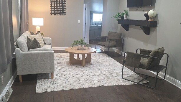 A living room with a grey sofa, a round coffee table, a patterned rug, and a TV mounted on the wall. - Spacious 3-bedroom house in serene Cleveland with AC (Cleveland)