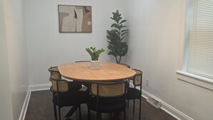 A dining area with a round table, six chairs, a potted plant, a painting on the wall, and a window with blinds. - Spacious 3-bedroom house in serene Cleveland with AC (Cleveland)
