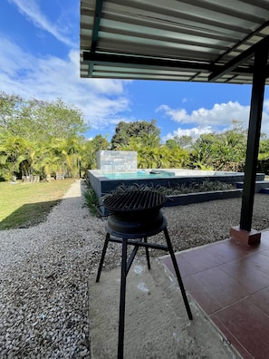 A barbecue grill under a covered patio area with a view of a swimming pool and lush greenery. - 🌋Near La Fortuna : Private villa with private pool surrounded by nature (Provincia de Alajuela)