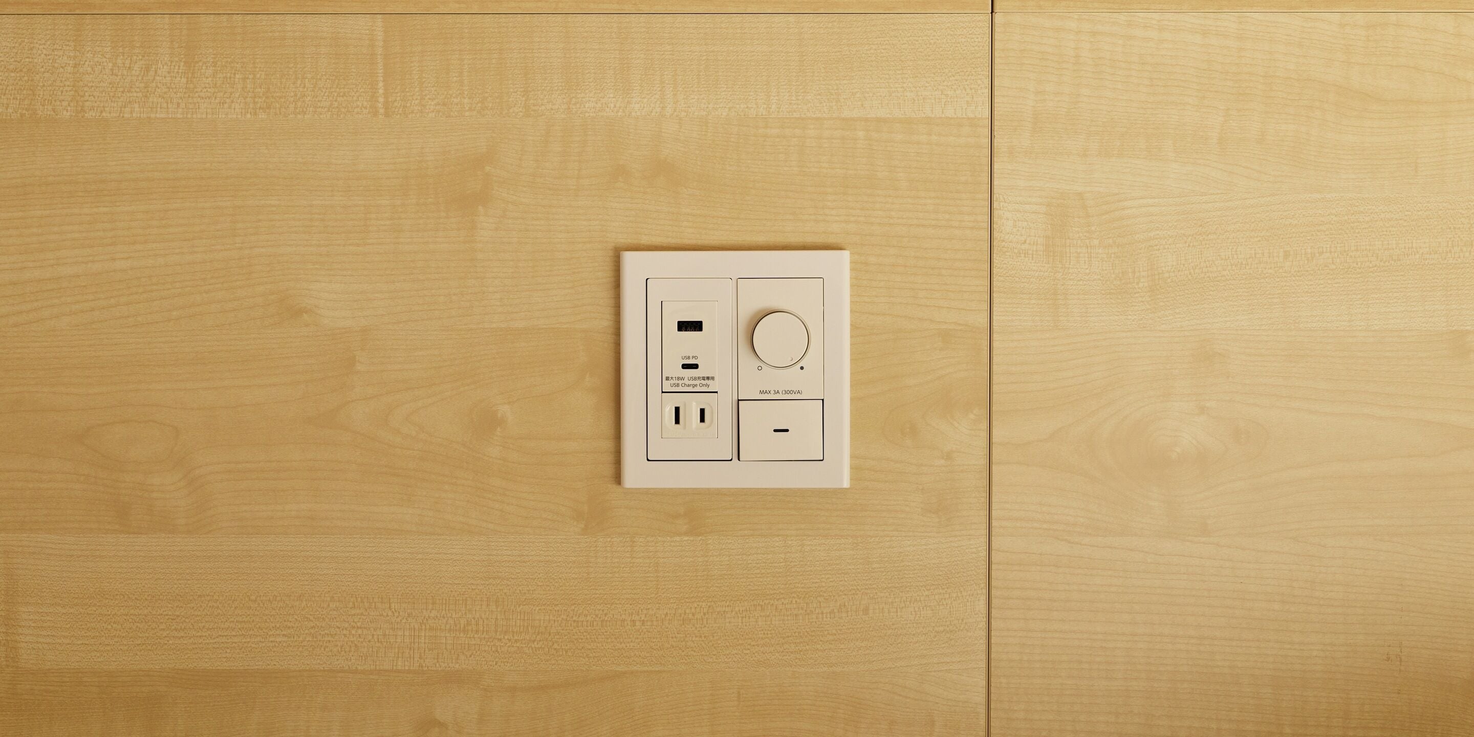 A wall-mounted electrical outlet with USB ports and a standard outlet, set in a wooden panelled room.