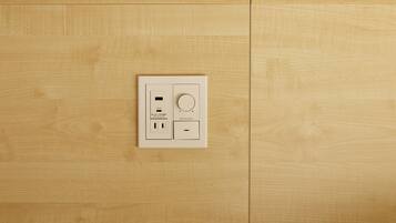 A wall-mounted electrical outlet with USB ports and a standard outlet, set in a wooden panelled room.