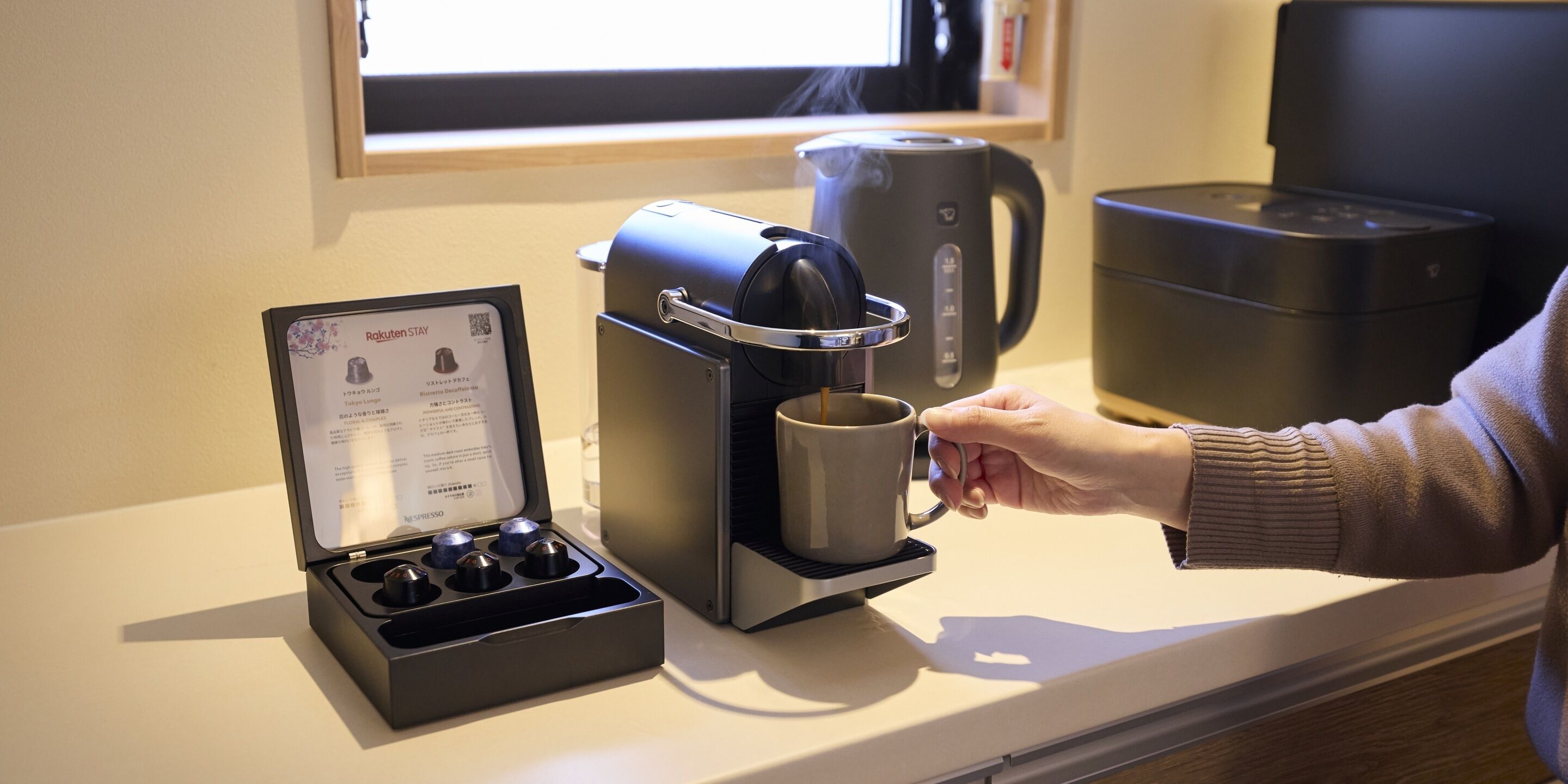 En kaffemaskin med en mugghållare, en vattenkokare och ett fack för kaffekapslar.