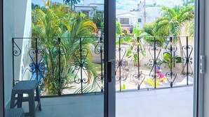 Un balcon donnant sur un quartier résidentiel, avec des maisons et des palmiers.