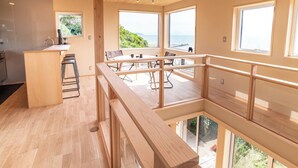 Une cuisine moderne avec un coin repas, de grandes fenêtres et une vue sur la mer.