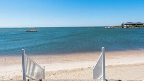 A beach with a clear view of the ocean, a sandy shore, and a building in the distance.