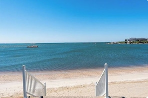 Una spiaggia con vista sull'oceano, una riva sabbiosa e un edificio in lontananza.