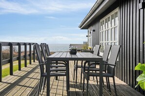 A wooden deck with a table and chairs, overlooking a body of water. - Summerhouse with fantastic panorama seaview (Faaborg)